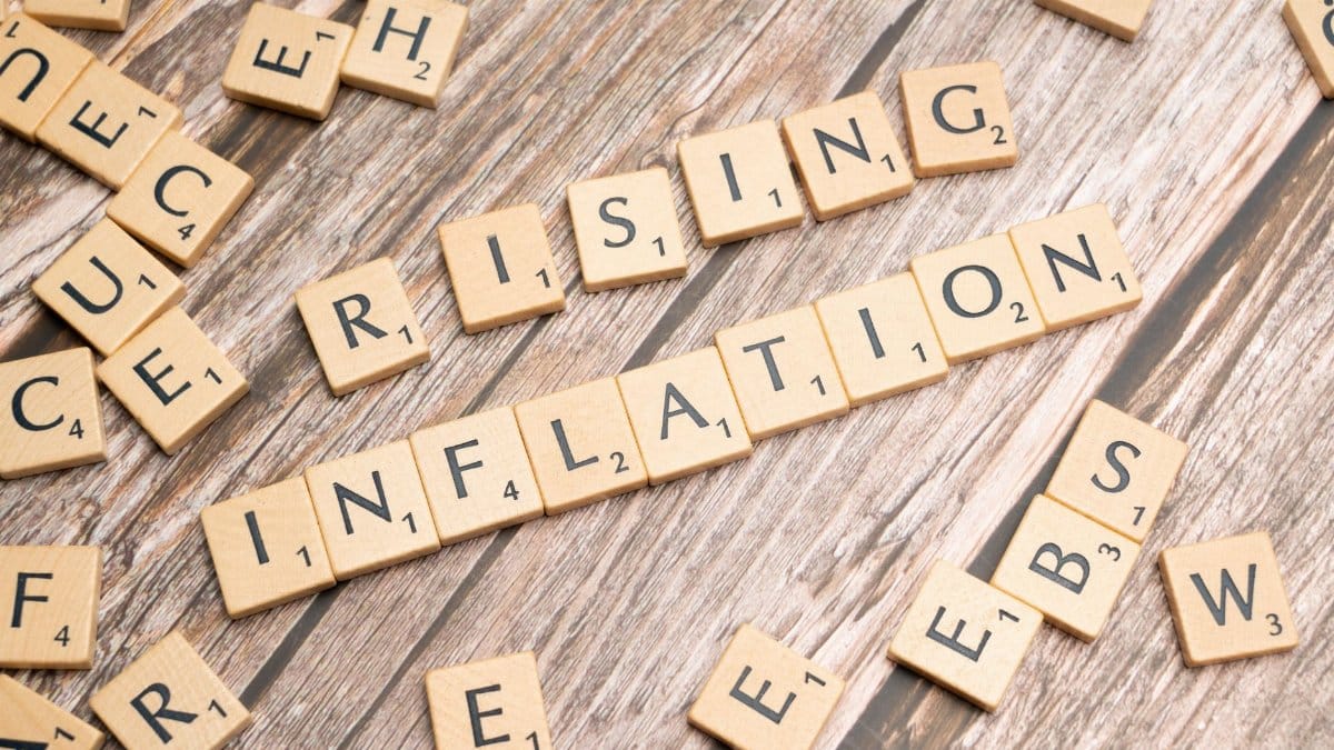 Wooden letter tiles spell 'rising inflation' symbolizing economic concerns.