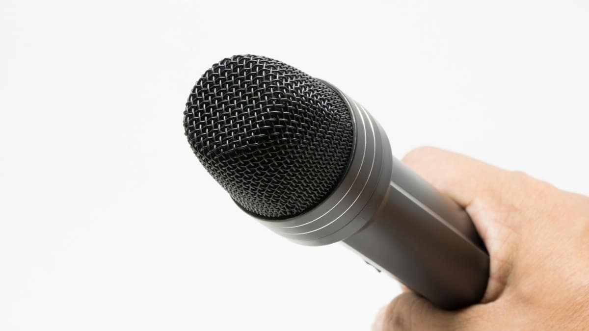 Close-up image of a microphone held in hand against a white background.
