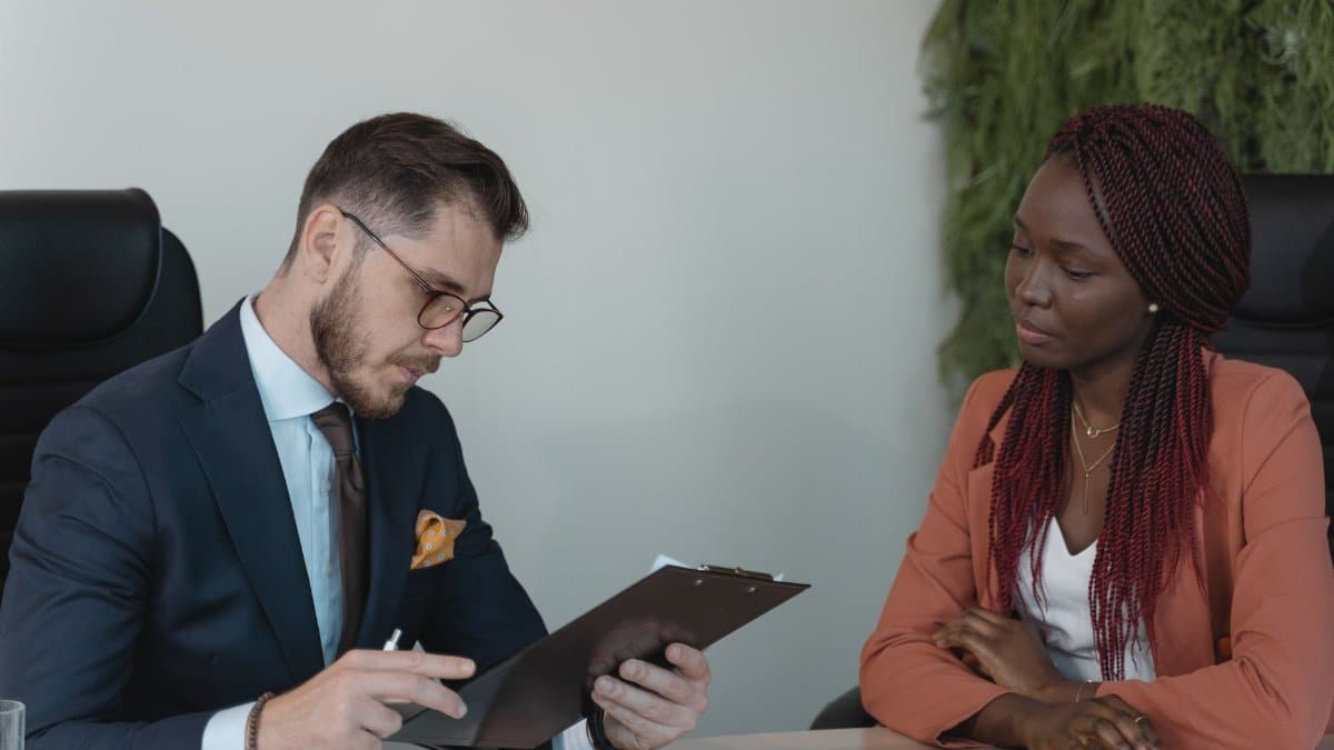 A man and woman engaging in a job interview in a modern office setting.