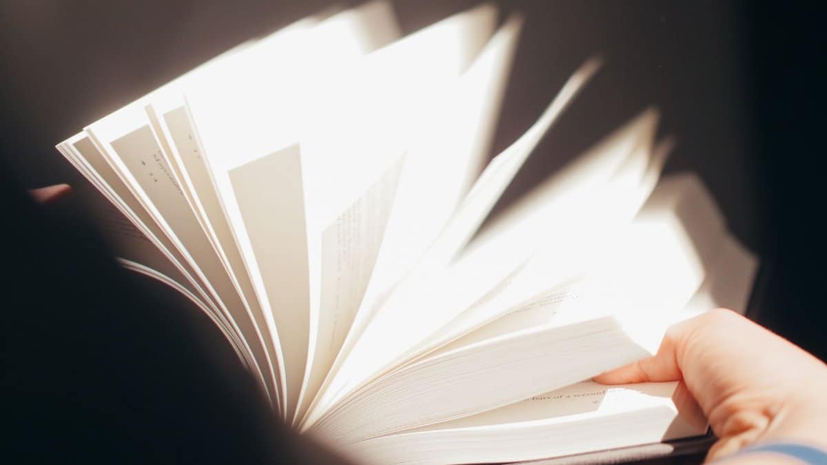 A detailed close-up image showing the dynamic flipping of book pages by hand.