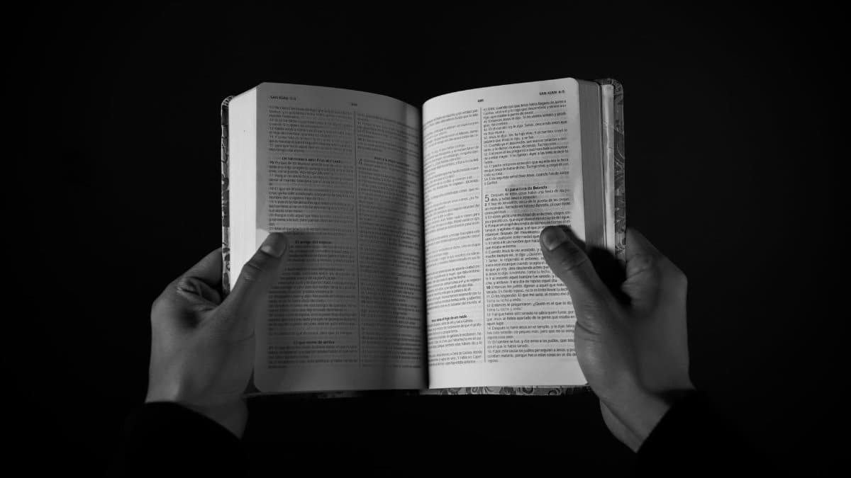 Black and white image showcasing hands holding an open book, symbolizing knowledge.