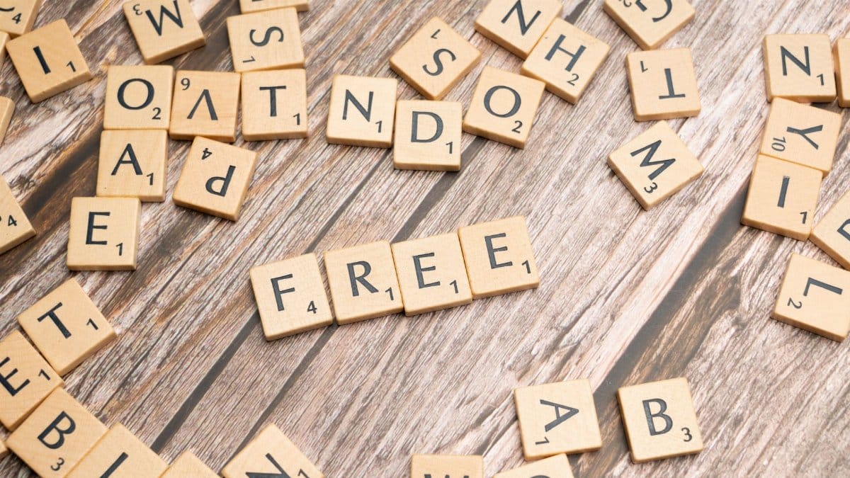 Scattered wooden letter tiles spelling 'FREE' placed on a rustic wooden floor.