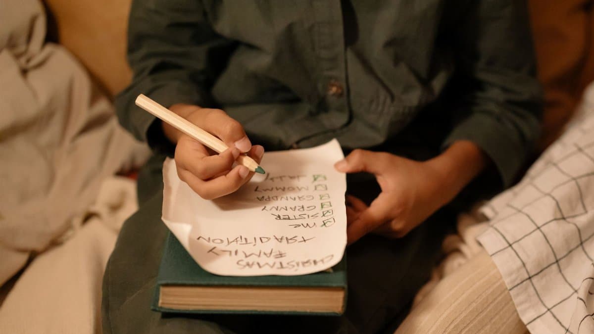 A child writes a Christmas wish list with green pencil on cozy winter evening. Family tradition and holiday joy.