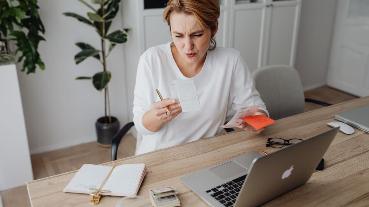 Woman reviewing documents at a desk, working intensely in a modern home office setting.