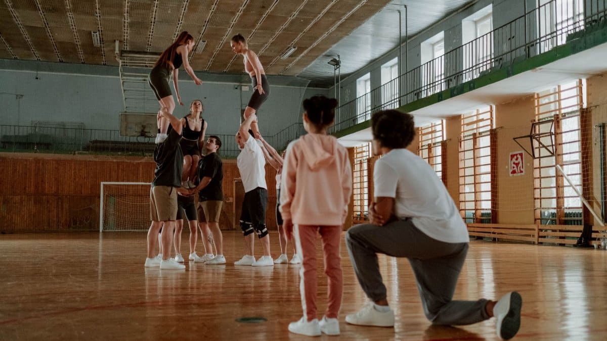 Group of athletes rehearsing cheerleading moves indoors.