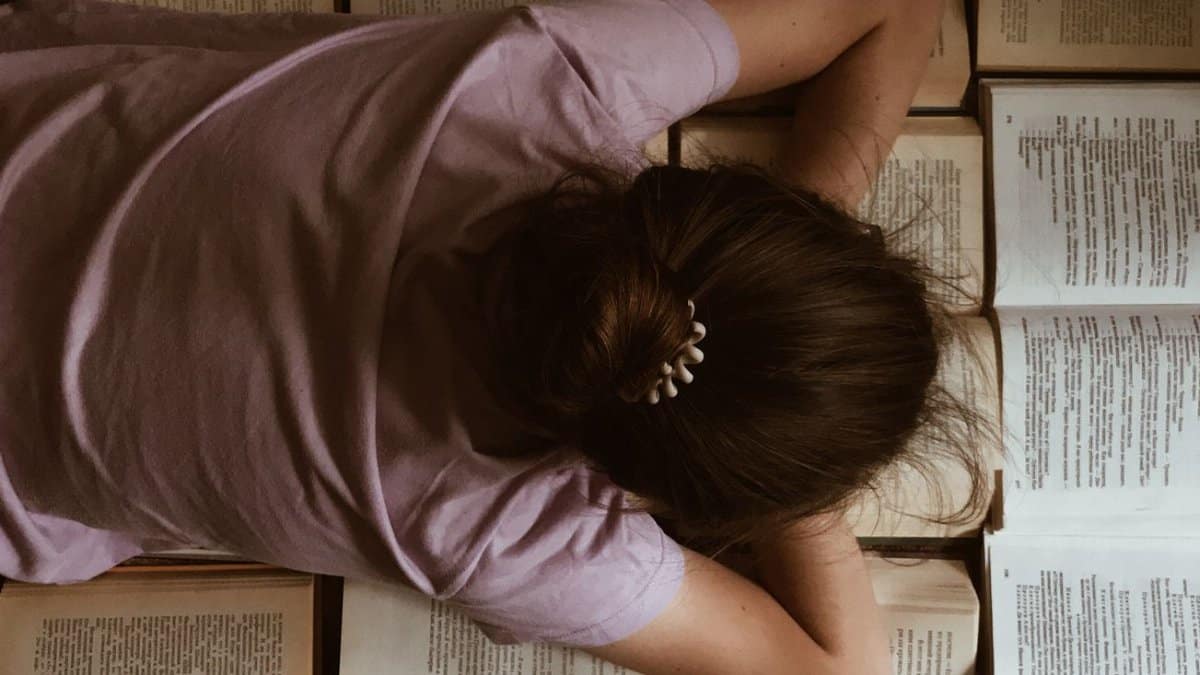 A woman lying on open books, enjoying a quiet reading session.