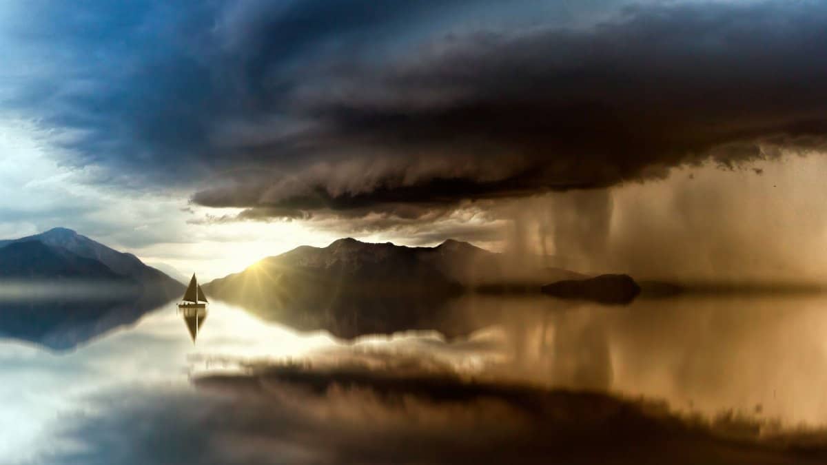 A majestic scene of a sailboat on a calm lake with dramatic storm clouds and sunset reflections.