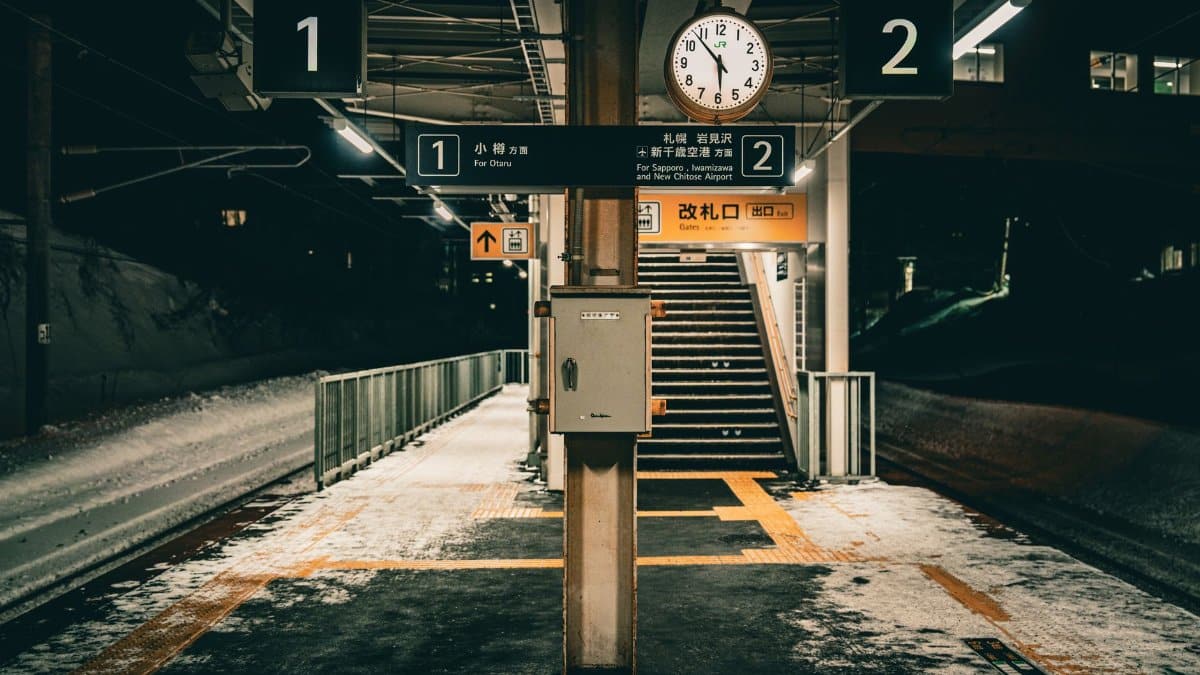 Winter night view of Otaru station platform in Hokkaido, Japan, featuring empty tracks and a clock.