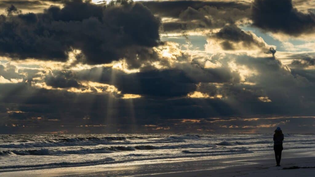 Stunning beach sunset in Destin, Florida with striking clouds and sun rays illuminating the ocean.