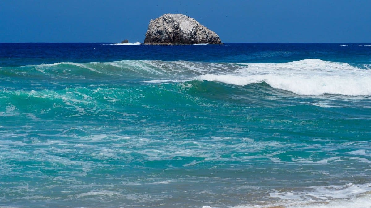 Vibrant ocean waves and rock formation off the coast of Oaxaca, Mexico.