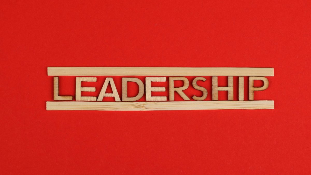 Wooden letters spelling leadership on a vibrant red background, conveying bold concepts.