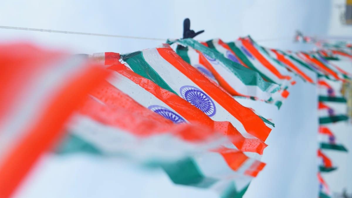 Line of Indian flags waving against a clear sky, symbolizing patriotism.