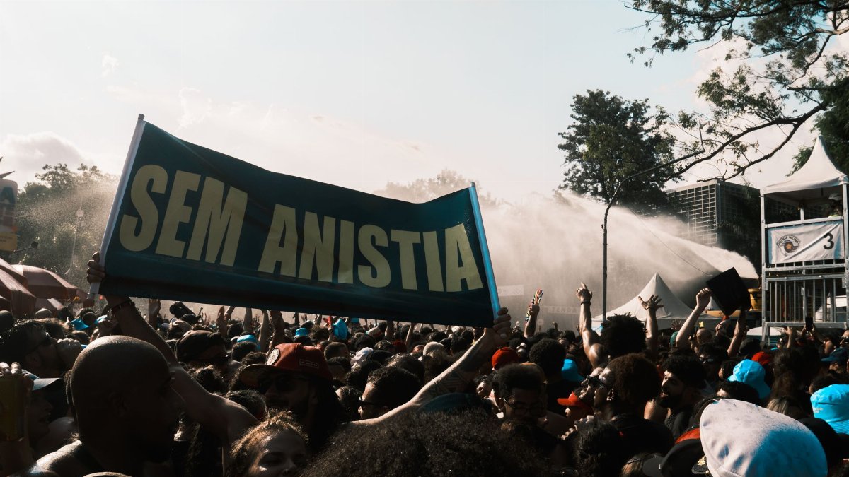 Large crowd demonstrating with a 'Sem Anistia' banner, conveying a powerful protest message.