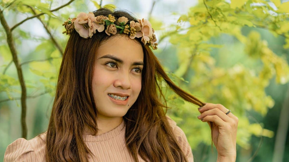 Portrait of a woman with a floral crown, smiling in an outdoor park setting.