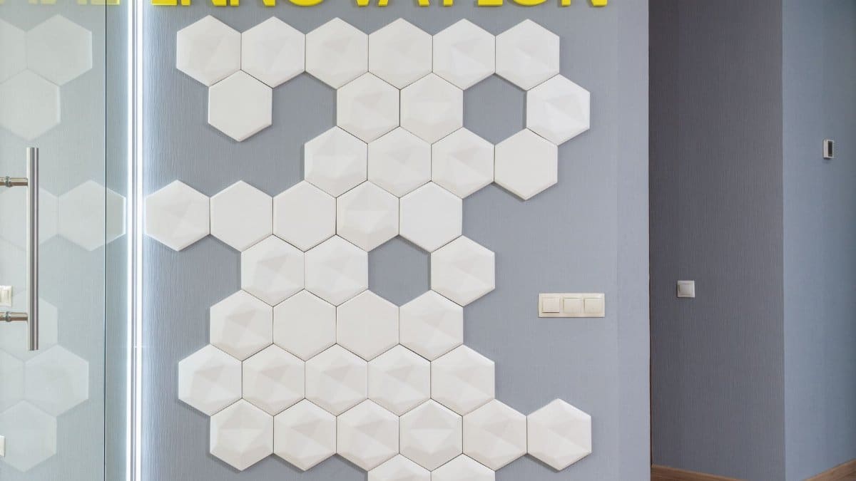 White geometric decorations on wall with yellow Innovation inscription in hallway of modern office building near glass door of room