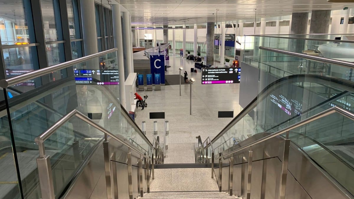 Spacious airport terminal featuring a modern staircase and glass railings enhancing architectural design.