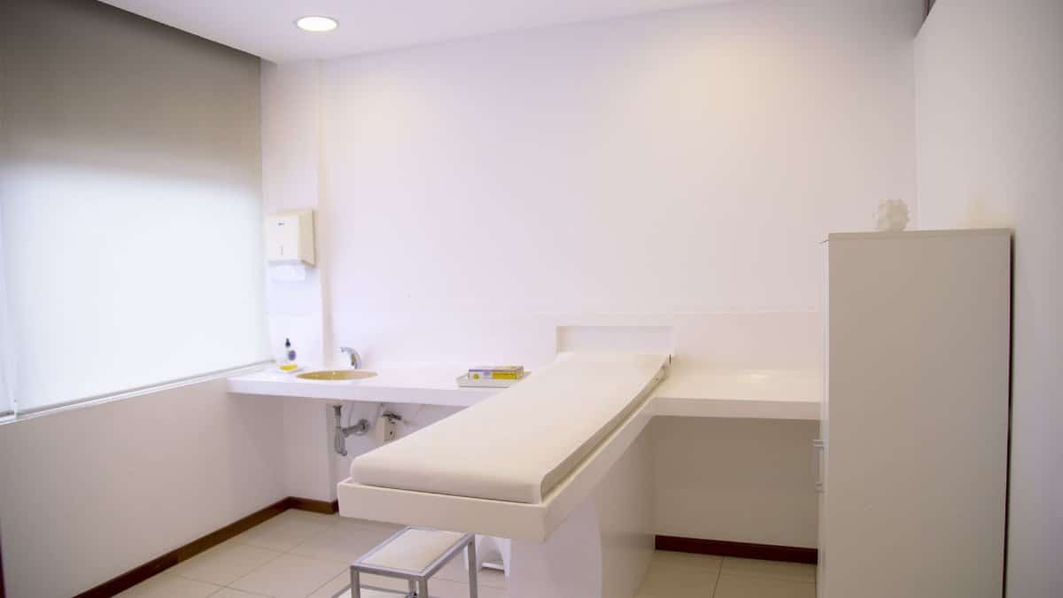 Minimalist white clinic room with examination table and furniture.