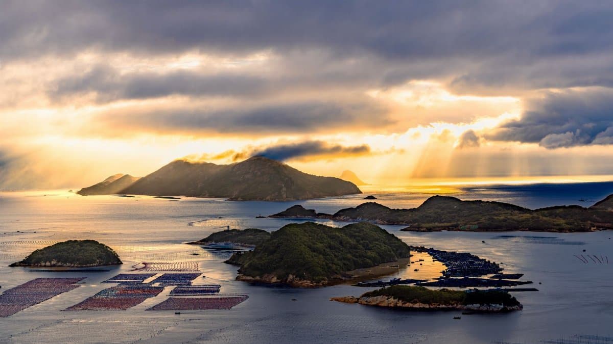 A stunning sunset view with golden rays shining over ocean islands and dramatic clouds.