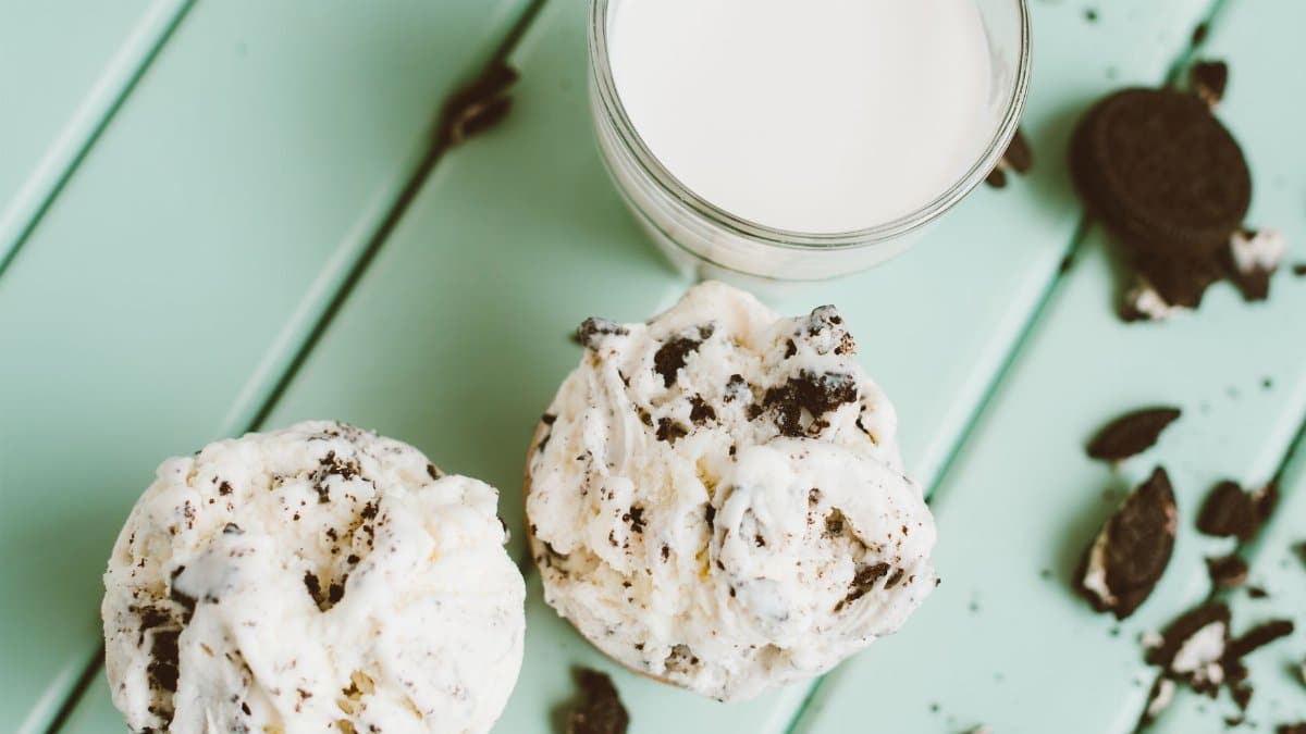 Delicious cookies and cream ice cream with a glass of milk, styled on a mint green background.