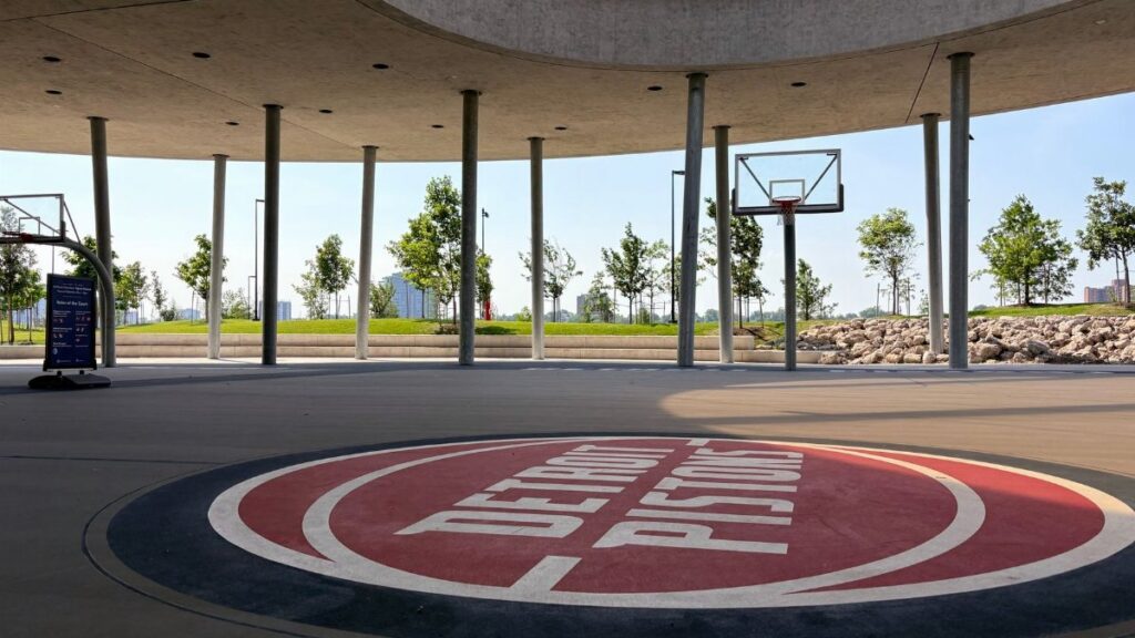 An outdoor basketball court featuring Detroit Pistons branding under a modern canopy.