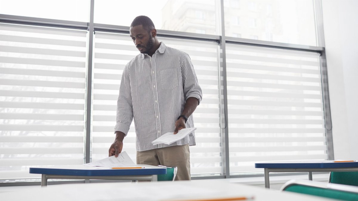 Educator sorting tests in a bright, contemporary indoor classroom setting.