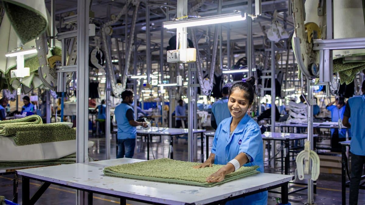 A cheerful factory worker arranges textiles in a well-lit manufacturing facility.