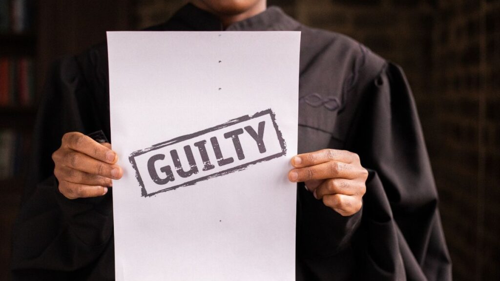 A judge in a courtroom holding a paper with a guilty verdict, symbolizing law and justice.