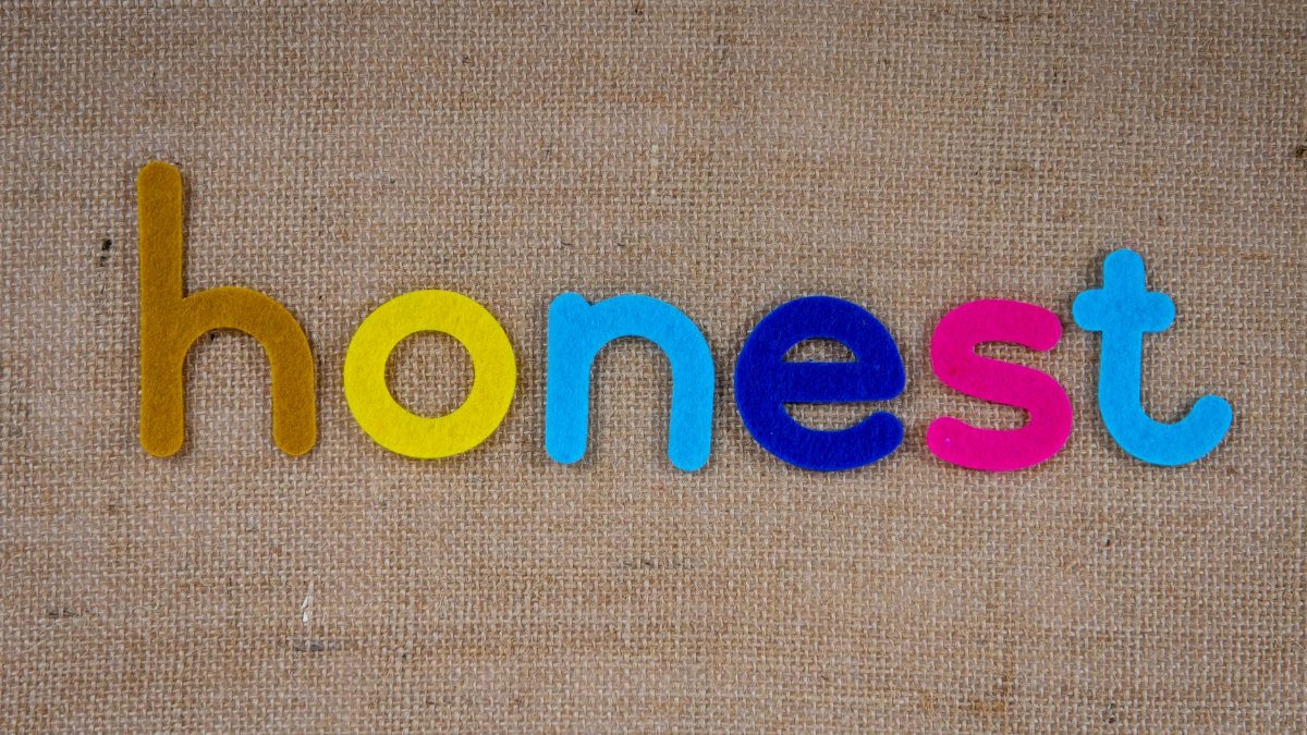 Bright felt letters spelling 'honest' on natural burlap background.