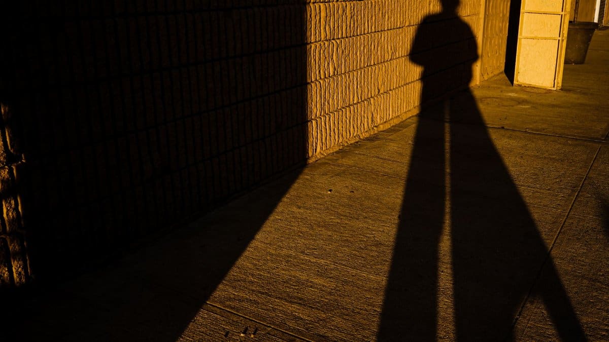 Dramatic long shadow of a person on an urban sidewalk during sunset, creating a mysterious mood.