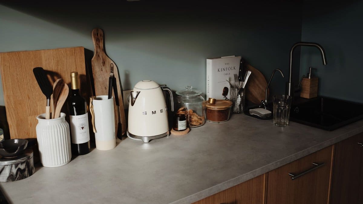 Composed utensils and appliance on gray stone counter of cozy kitchen in beam of soft sunlight