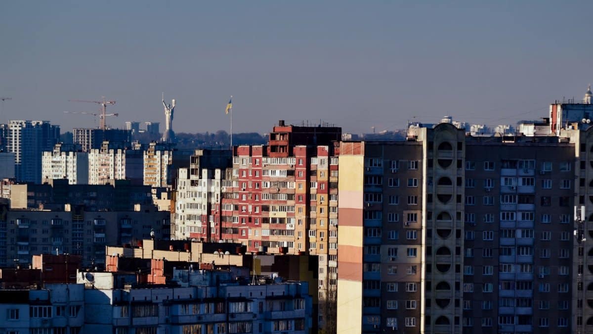 Aerial view of Kyiv's skyline featuring Soviet-era apartment blocks and the Motherland Monument.