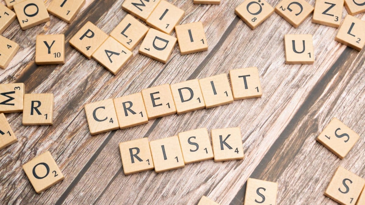 Scattered wooden letter tiles spelling 'credit risk' on a rustic wooden surface.