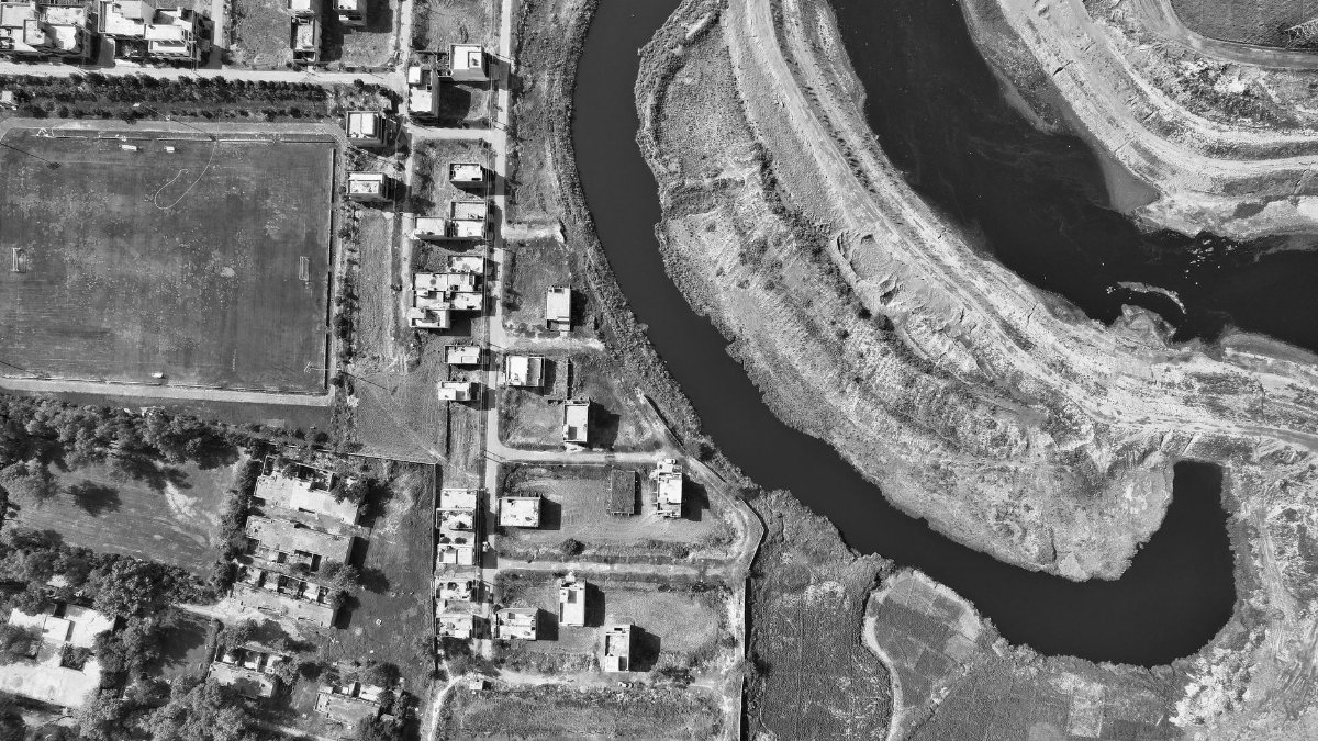 Black and white aerial shot of a river winding near houses in Kala Shah Kaku, Pakistan.