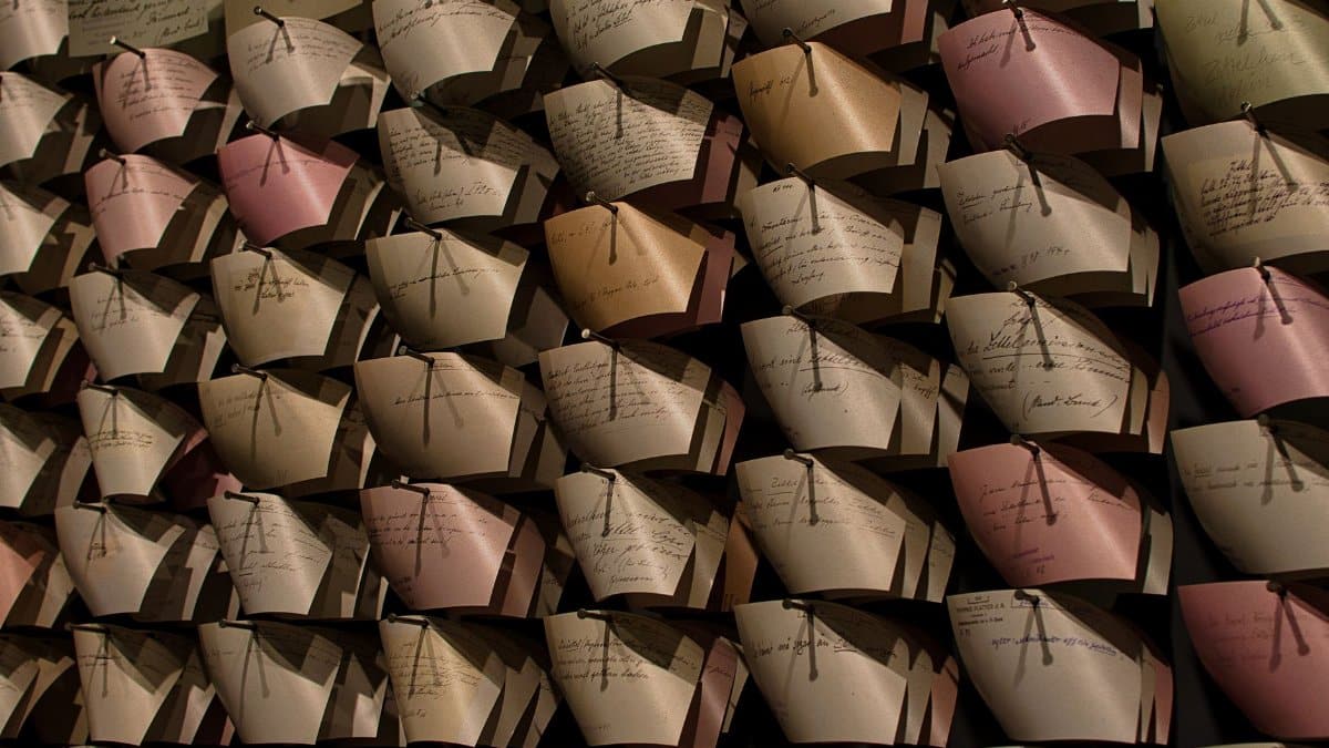 Close-up of a wall filled with organized vintage letters in a pattern, showcasing handwritten notes.