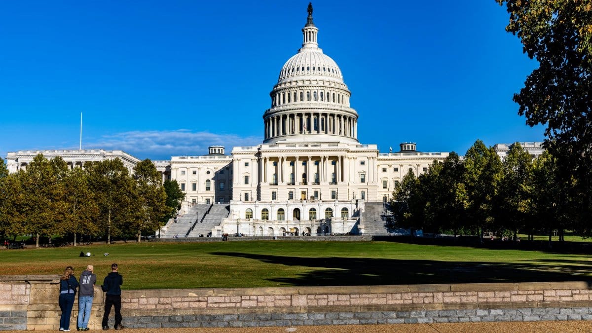 A vibrant daytime photograph of the iconic US Capitol with a clear blue sky backdrop.
