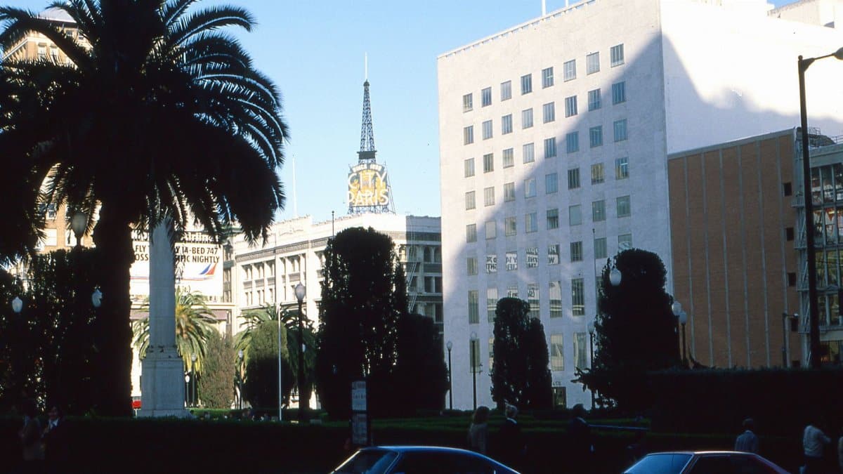 A city square with architectural buildings, palm trees, and clear blue sky captured during the day.
