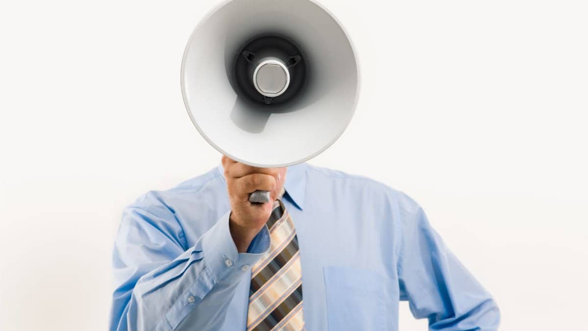 Businessman in blue shirt holding megaphone, symbolizing leadership and communication.