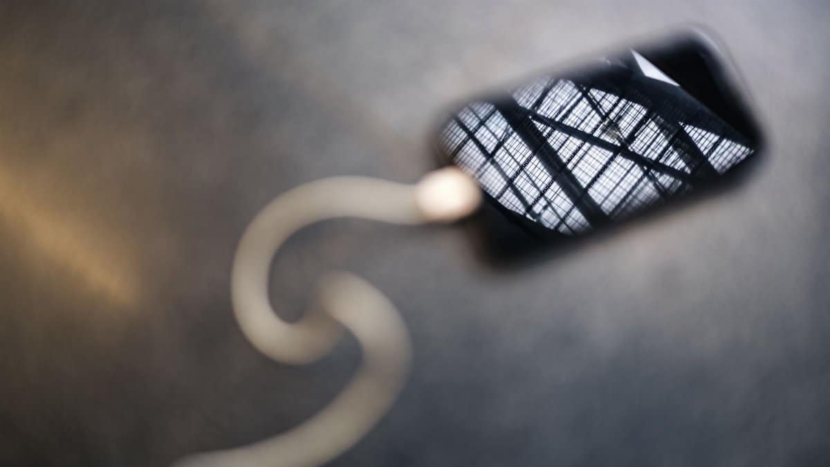 Smartphone showing architectural reflection, positioned with a white cable against a blurred background.