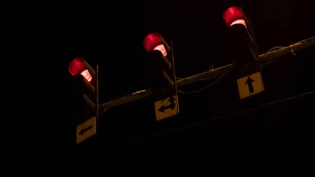 Three red traffic lights glowing brightly against a dark night sky, creating a vivid contrast.