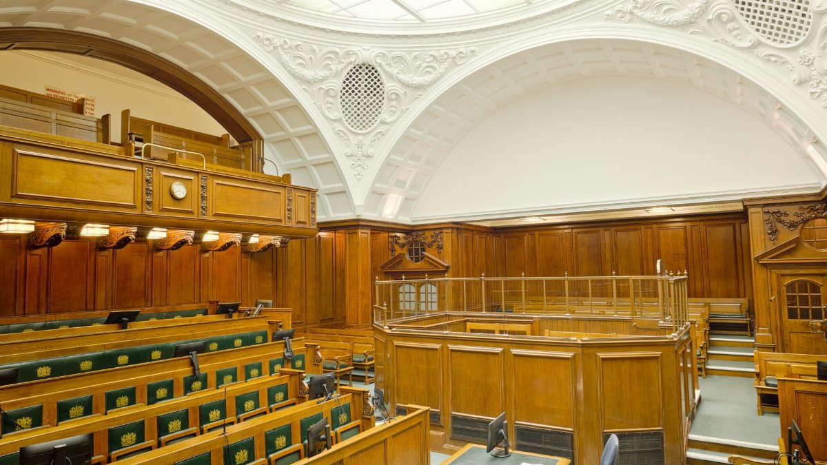Interior view of a historic courtroom in London with ornate design and wooden furnishing.