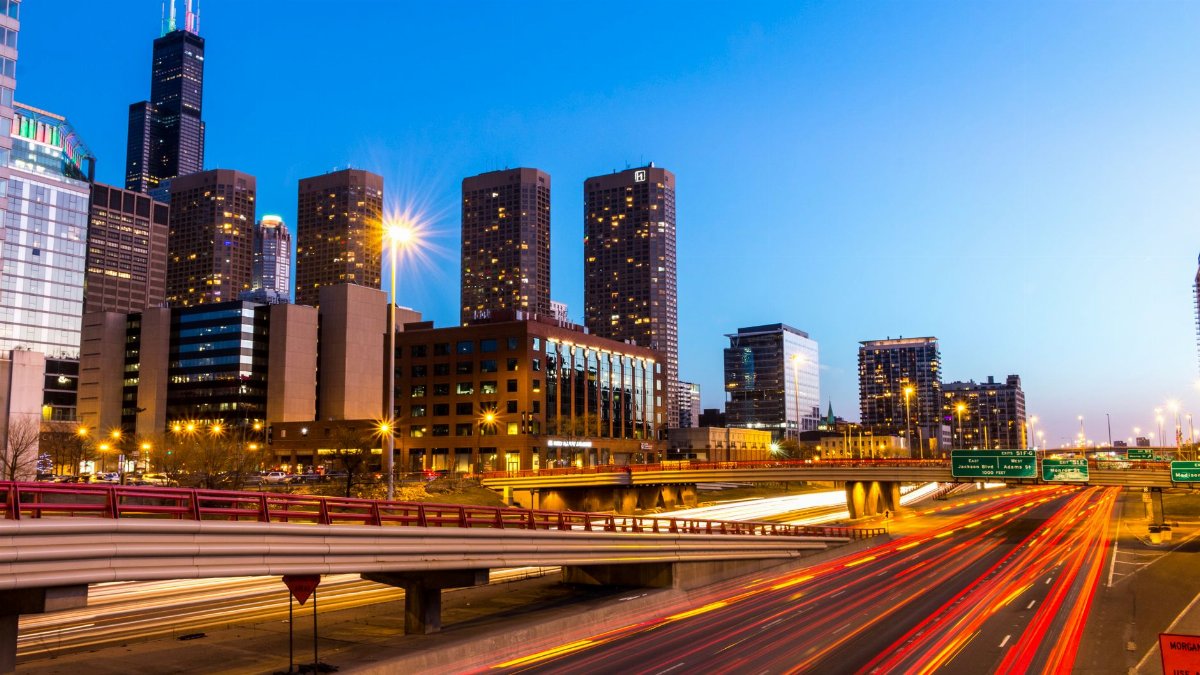 A vibrant view of Chicago's skyline with illuminated highways capturing light trails during twilight.