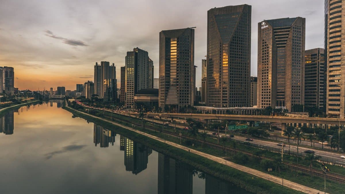 Stunning skyline of modern skyscrapers reflecting in the river at dusk, creating a peaceful cityscape.