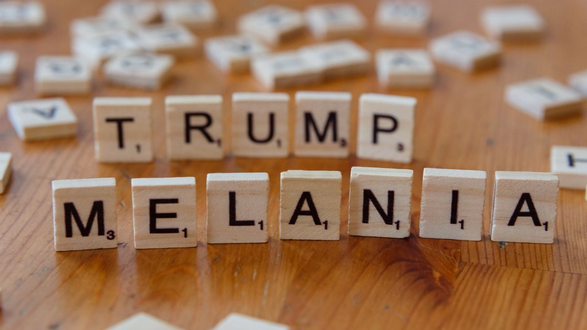 Wooden tiles arranged with letters spelling 'TRUMP' and 'MELANIA' on a table.