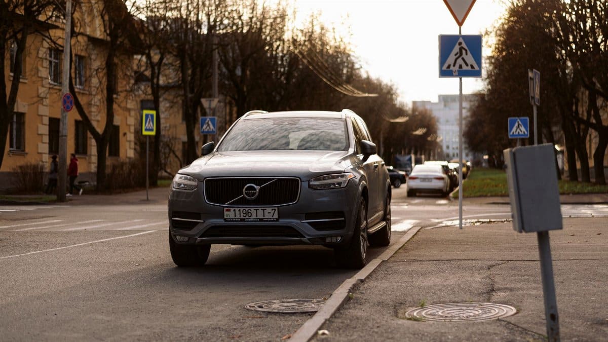 A Volvo XC90 parked on a city street surrounded by road signs. Urban setting with natural daylight.