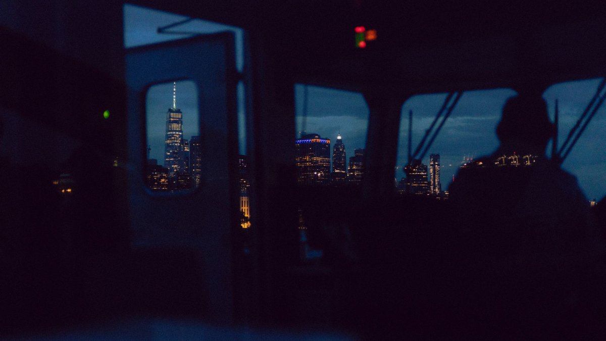 Moody cityscape view of One World Trade Center from a reflective vantage point during twilight.