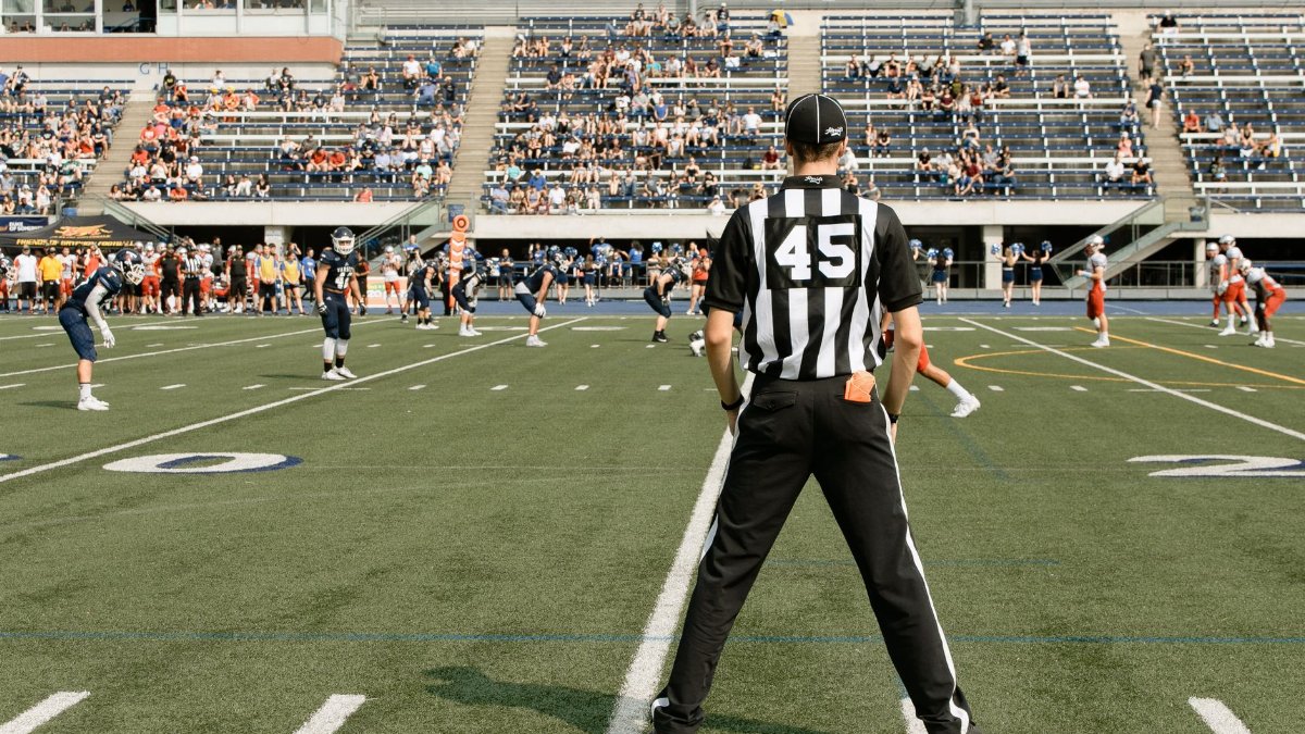 American football game with referee and players in action at a stadium in Toronto, Canada.