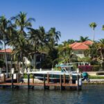 Scenic view of luxury waterfront homes with palm trees and a boat docked in Fort Lauderdale, Florida.