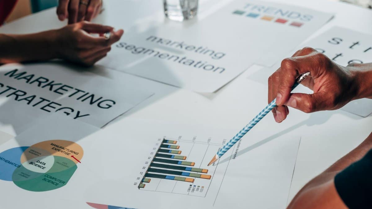 Team working on marketing strategy using data charts and papers in an office meeting.