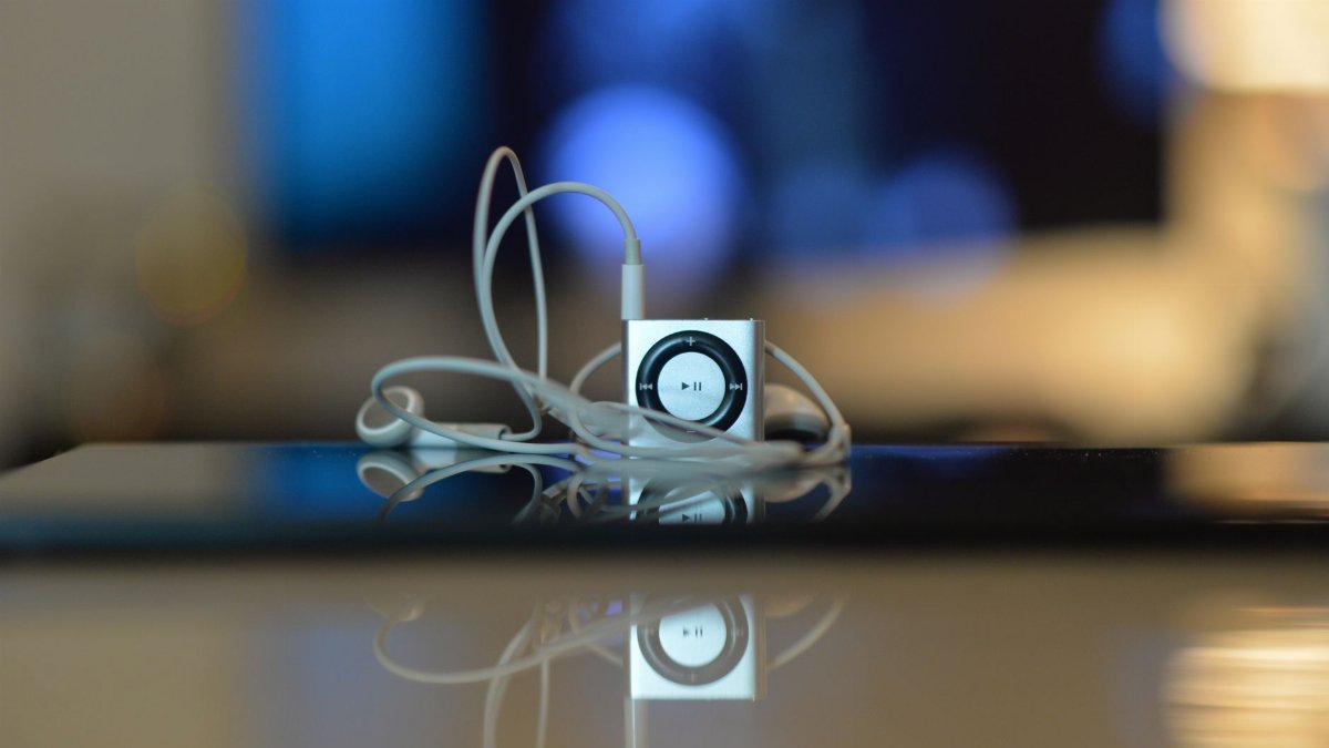 Photo of a small music player with reflective surface and earbuds, showcasing minimalist design.