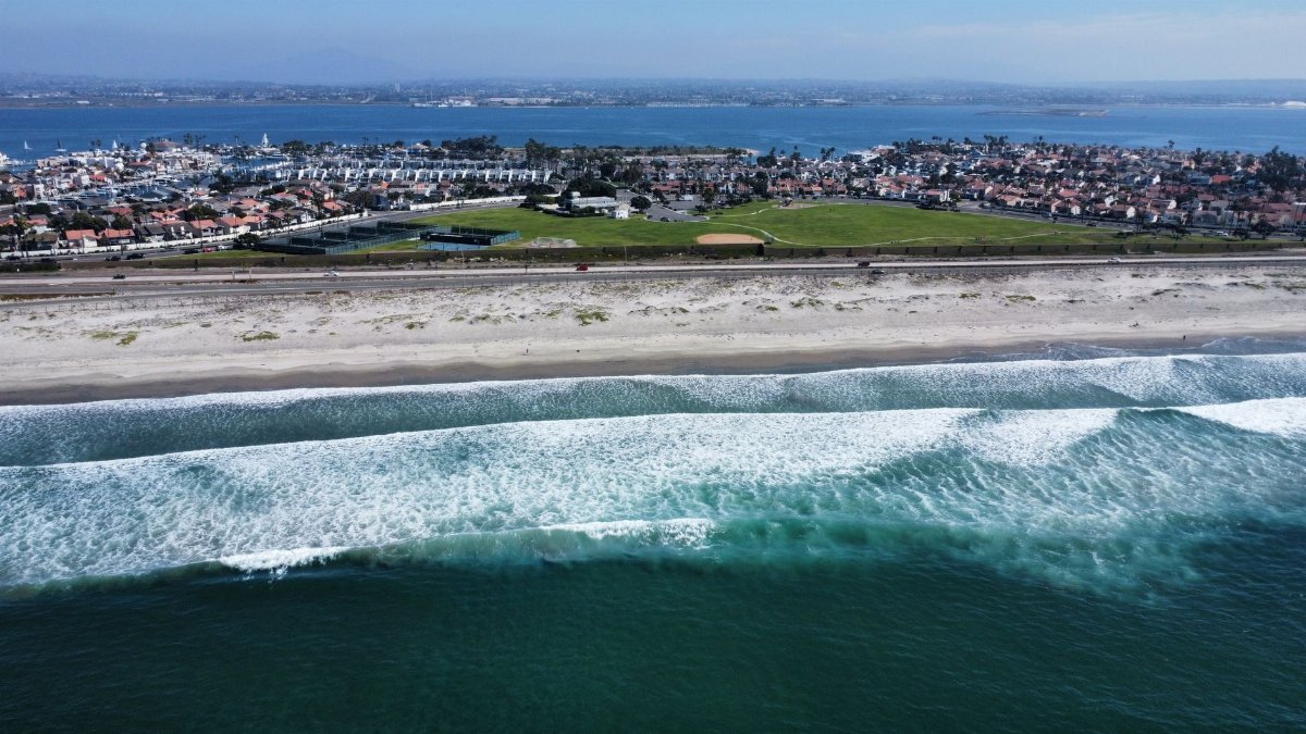 Stunning aerial capture of a coastal city with beachfront and waves.